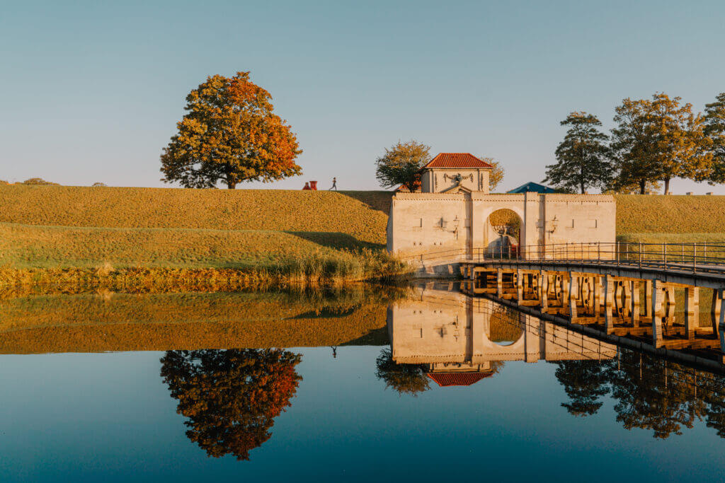 Eine Brücke über Wasser mit einem Gebäude und Bäumen.