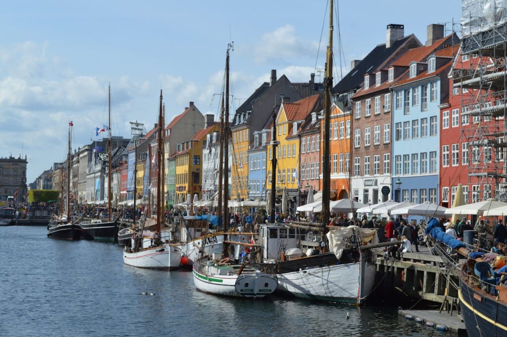 Lebendige Uferpromenade des Nyhavn-Hafens mit historischen Gebäuden und Booten in Kopenhagen.