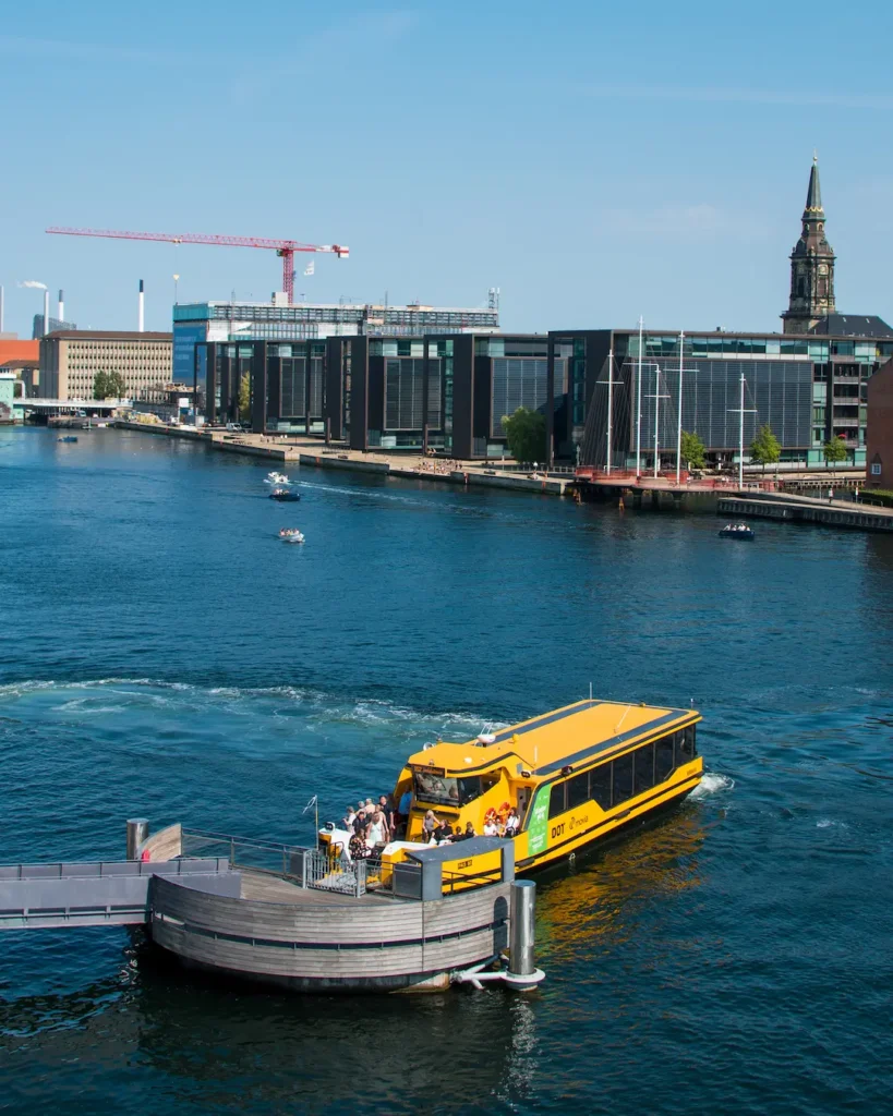 Hafenbus Kopenhagen Ein Wasserbus dockt an eine Haltestelle auf Wasser an.