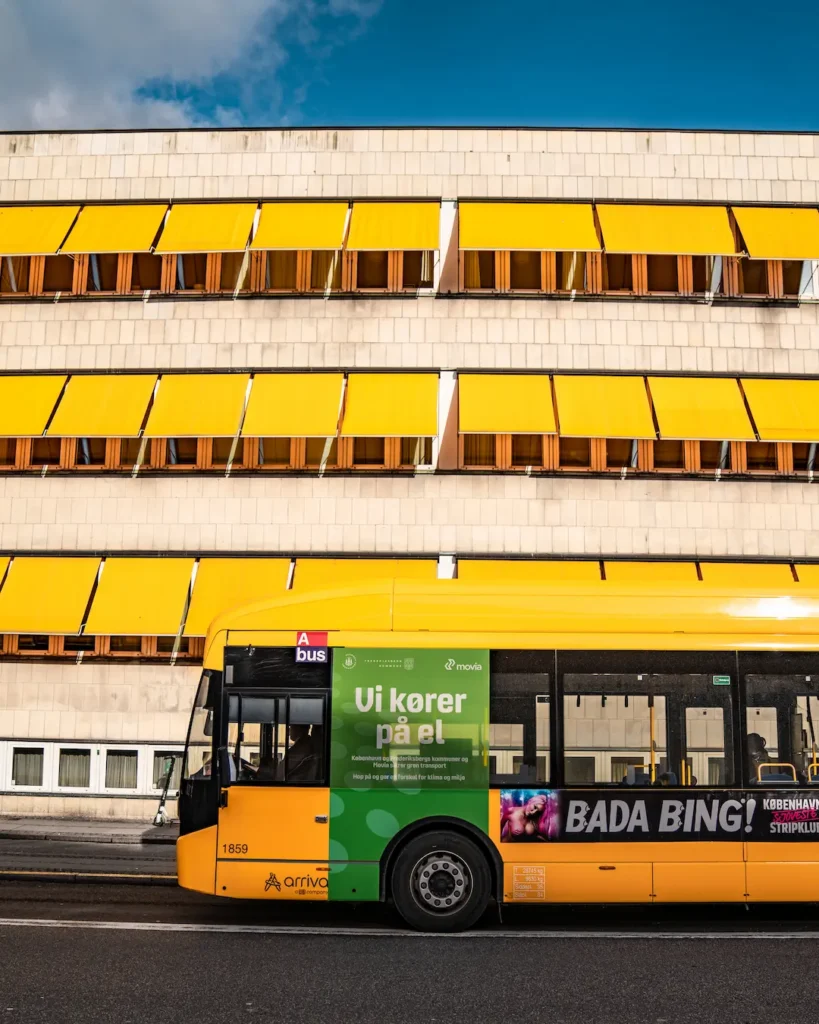 Bus Nahverkehr Kopenhagen Ein gelber Bus vor einem Gebäude mit gelben Markisen.