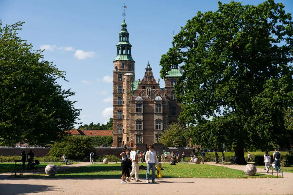 Schloss Rosenborg Kopenhagen Eine Gruppe von Menschen steht in einem Park mit dem Schloss Rosenborg im Hintergrund.